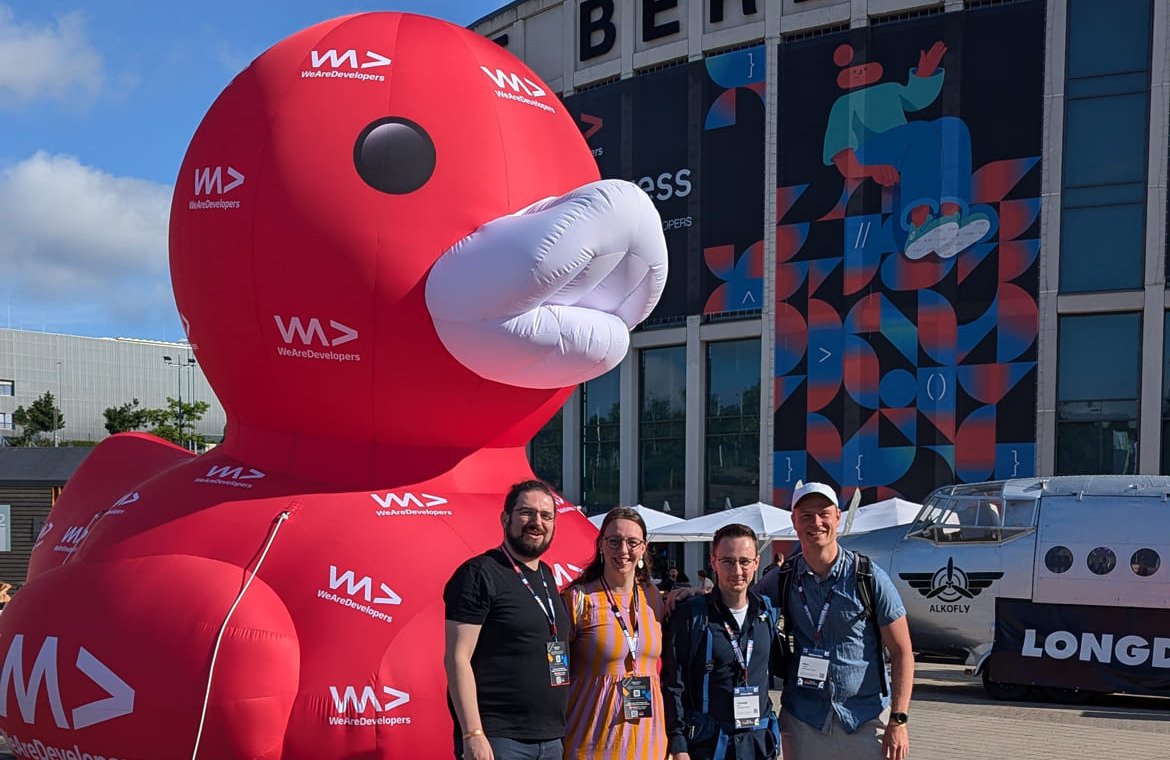 clickstorm beim WeAreDevelopers World Congress in berlin 2024: 4 Kollegen vor eine riesigien roten Gummi-Ente mit den WWC Logo